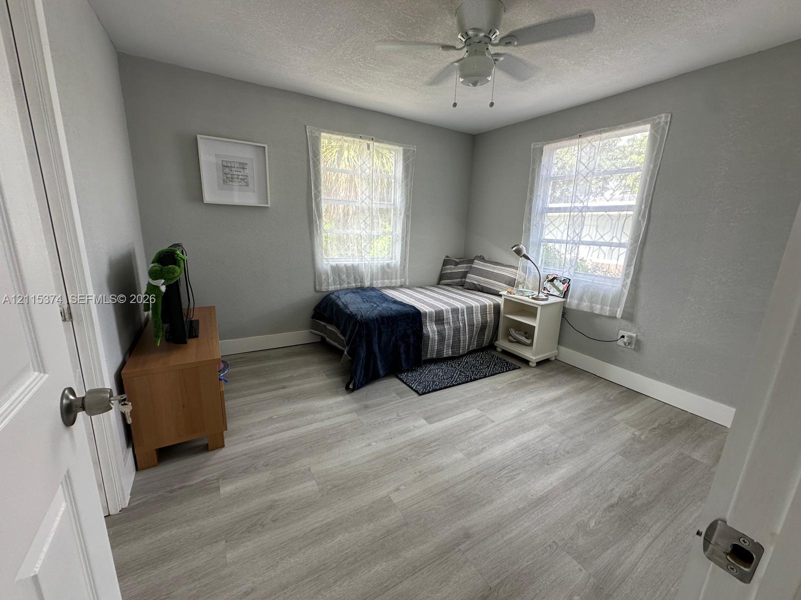 Bedroom featuring wood-finish flooring, dual windows, and a ceiling fan