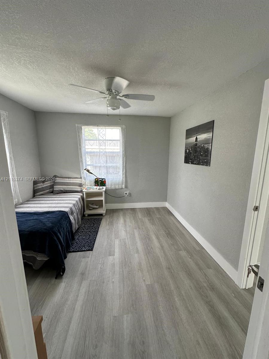 Wood-finish flooring, neutral wall tones, and ceiling fan fixture