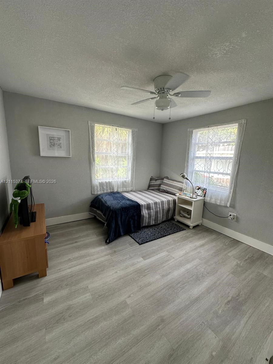 Room featuring wood-finish flooring, two windows with natural light, and a ceiling-mounted fan