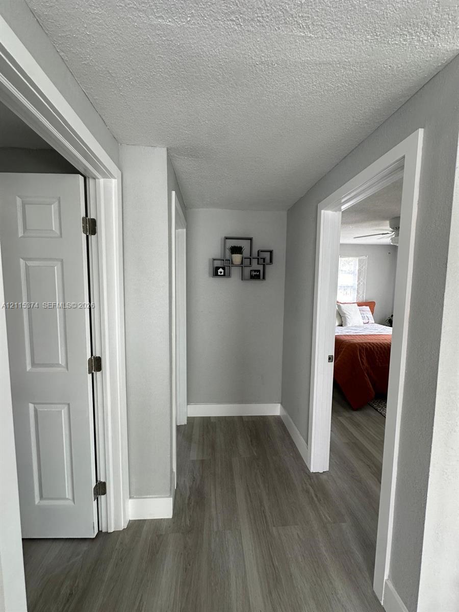 Hallway featuring neutral-toned walls, wood-finish flooring, and crisp white door casings with four-panel interior doors