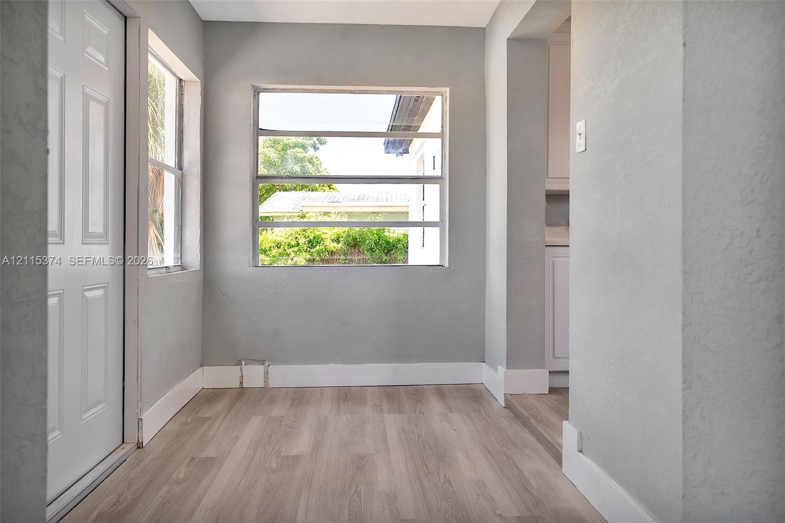 Neutral-toned interior featuring wood-finish flooring, crisp white trim, and multiple horizontal slider windows