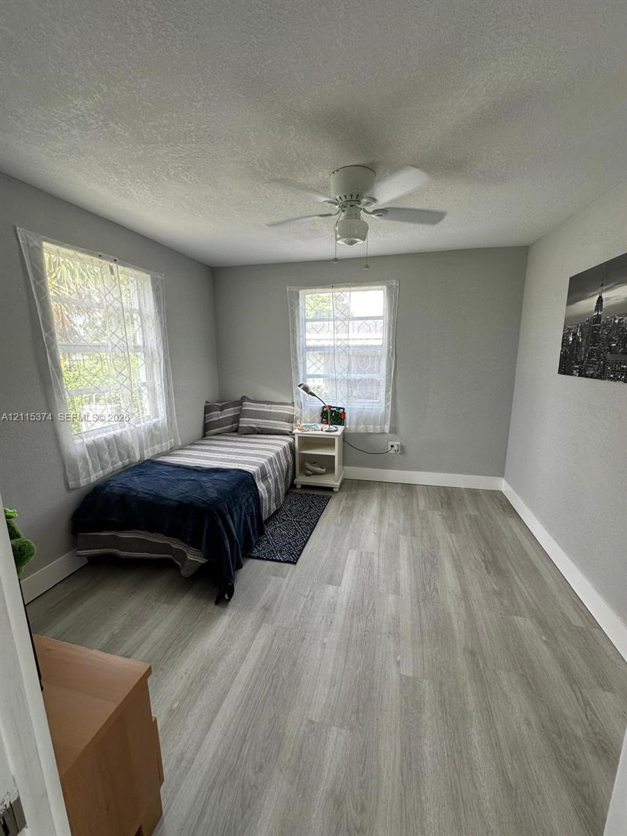 Neutral-toned interior featuring wood-finish flooring, dual windows, and a ceiling-mounted fan