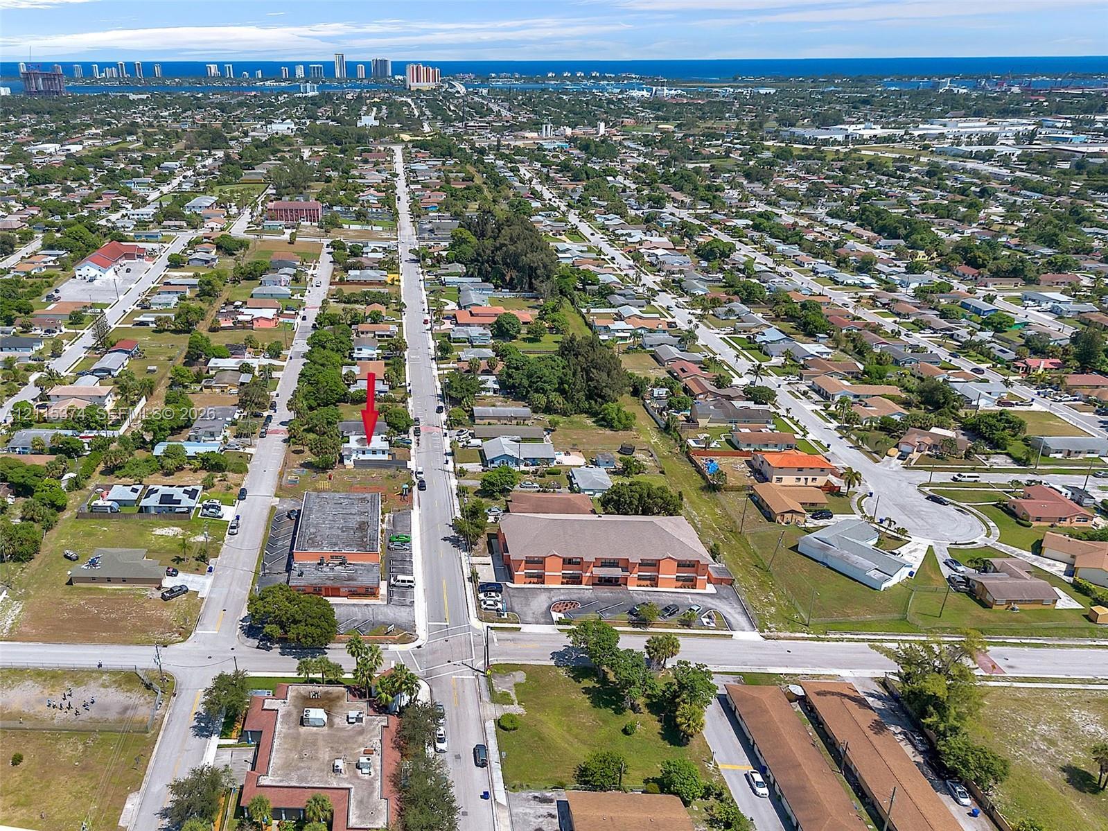 Aerial perspective featuring a property situated on a corner lot with frontage on a primary roadway and proximity to coastal waters