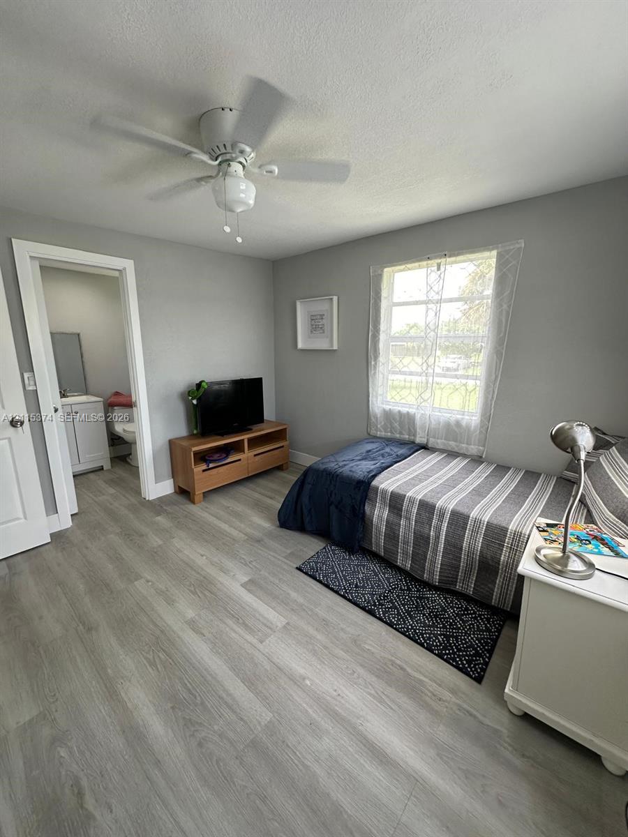 Wood-finish flooring, ceiling fan with integrated light fixture, single-hung window, and neutral wall tones