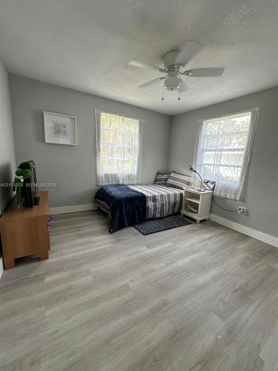 Room featuring wood-finish flooring, dual windows, and a ceiling fan