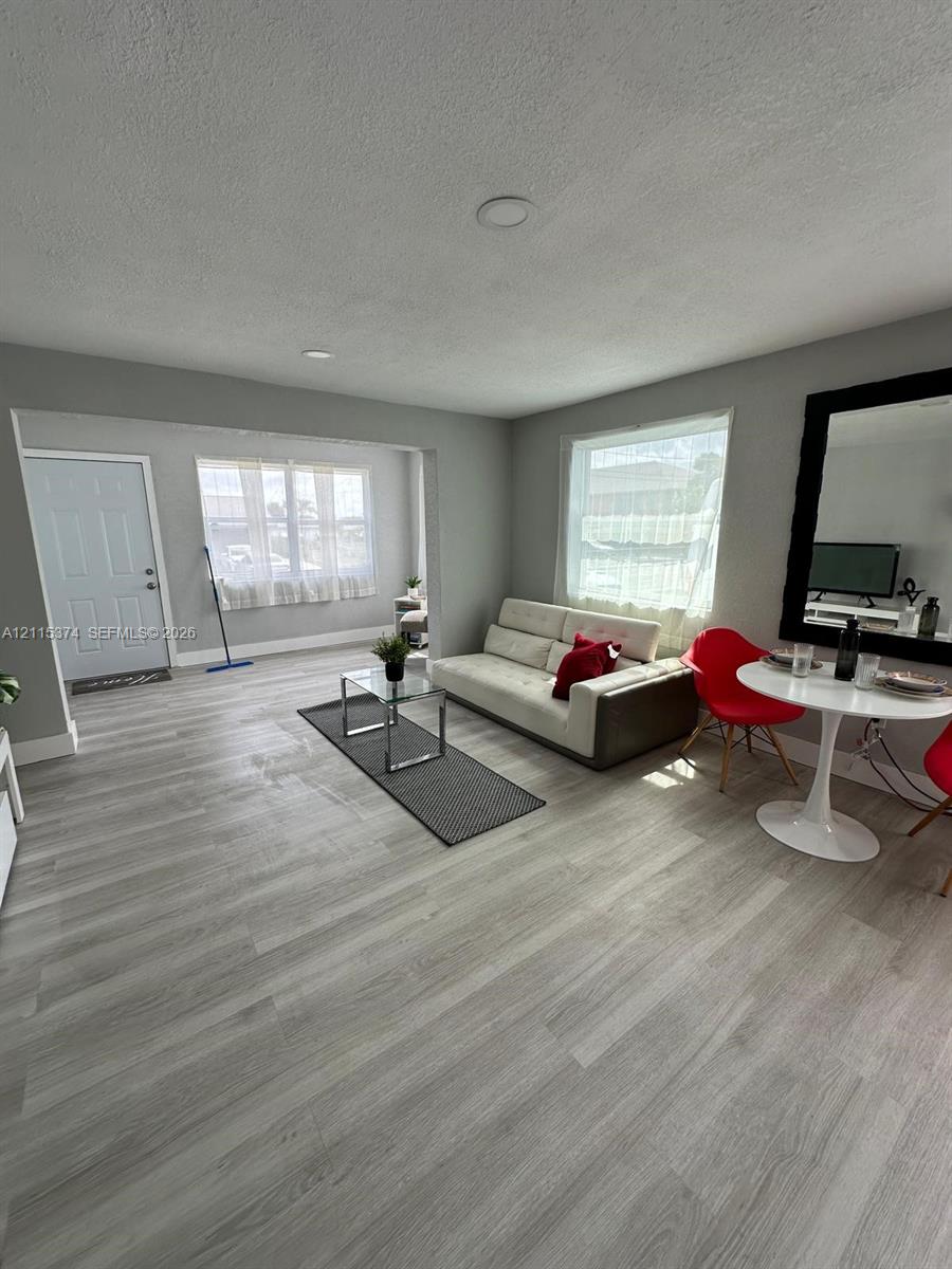Open-concept room featuring light-toned wood-finish flooring, recessed lighting, and large windows providing natural illumination