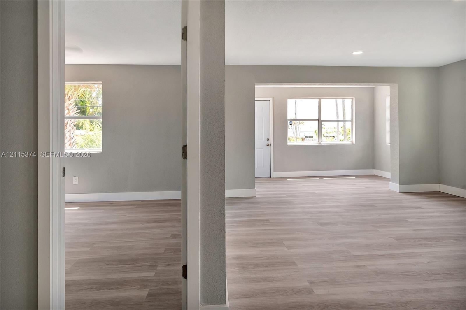 Interior space featuring light-tone wood-finish flooring, neutral wall paint, multi-pane windows, and recessed lighting