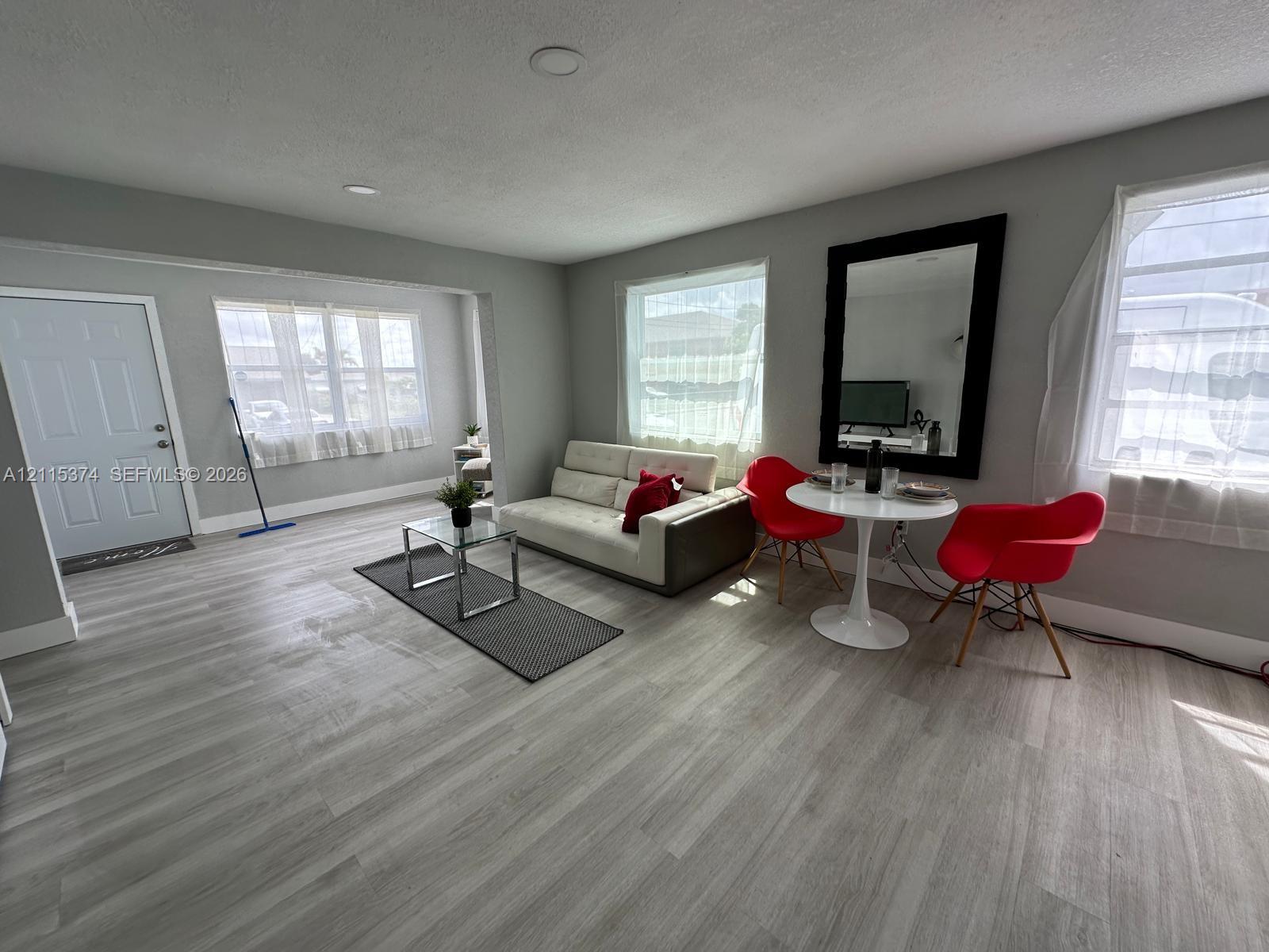 Open-concept interior featuring light wood-finish flooring, recessed lighting, and multiple windows with white trim