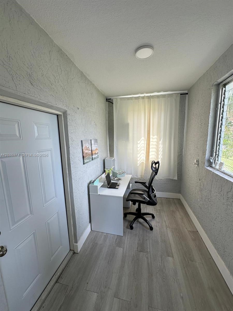 Textured walls, wood-finish flooring, and a single-pane window with a metal security grill