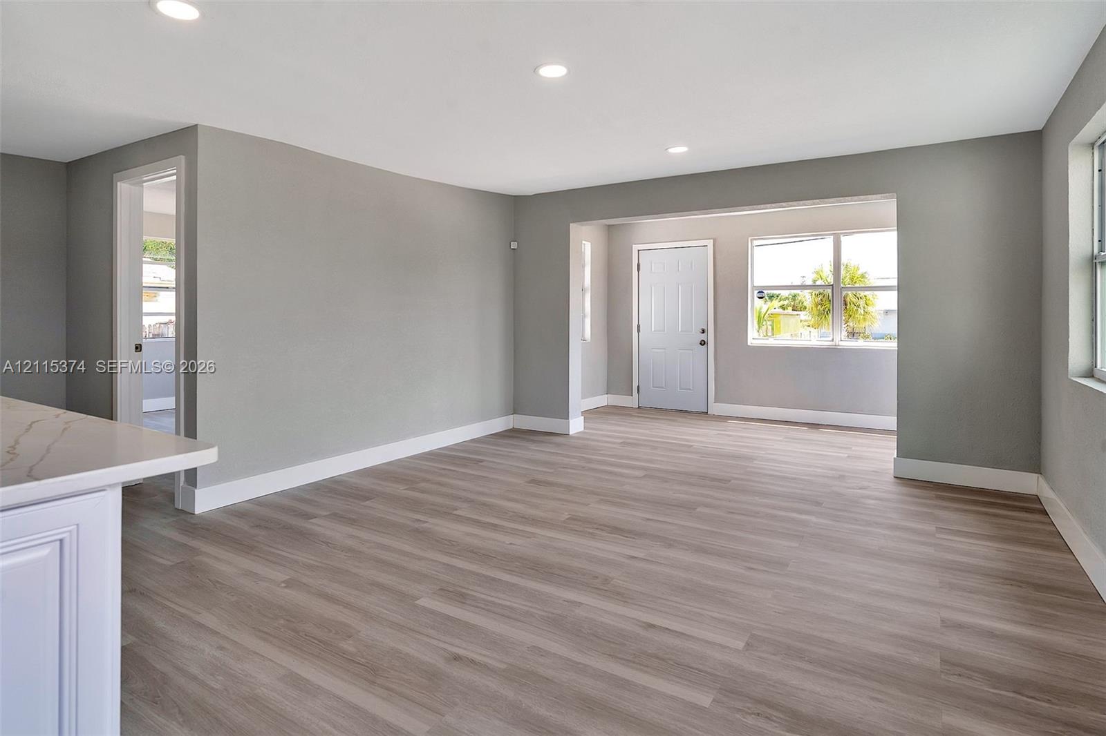 Interior space featuring neutral-toned walls, wood-finish flooring, recessed lighting, and multi-pane windows