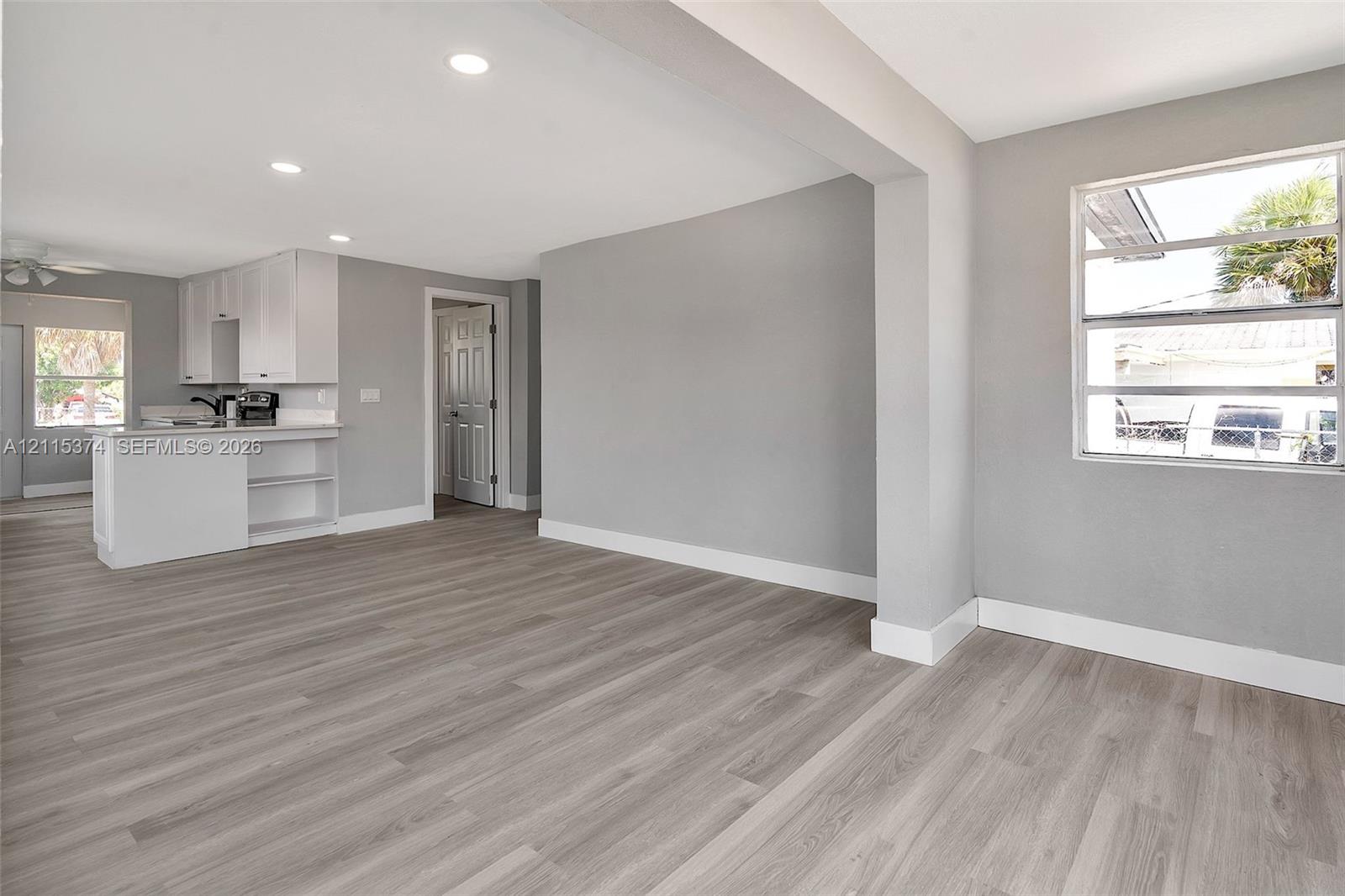 Neutral-toned interior featuring wood-finish flooring, recessed lighting, white cabinetry, and horizontal sliding windows