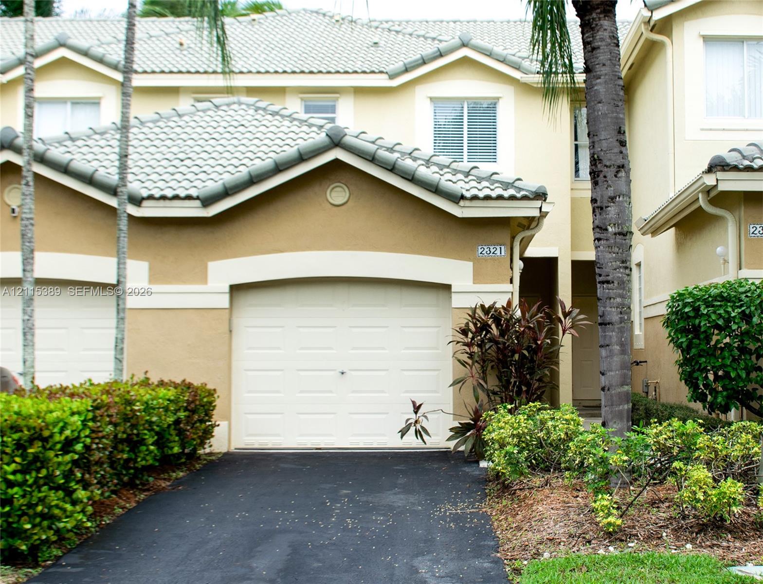 Exterior featuring a dual-pitch tile roof, arched garage entrance, and multi-pane windows