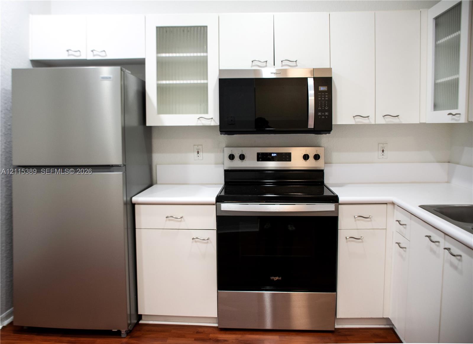Kitchen featuring white cabinetry with glass-panel accents, and a full suite of stainless steel appliances
