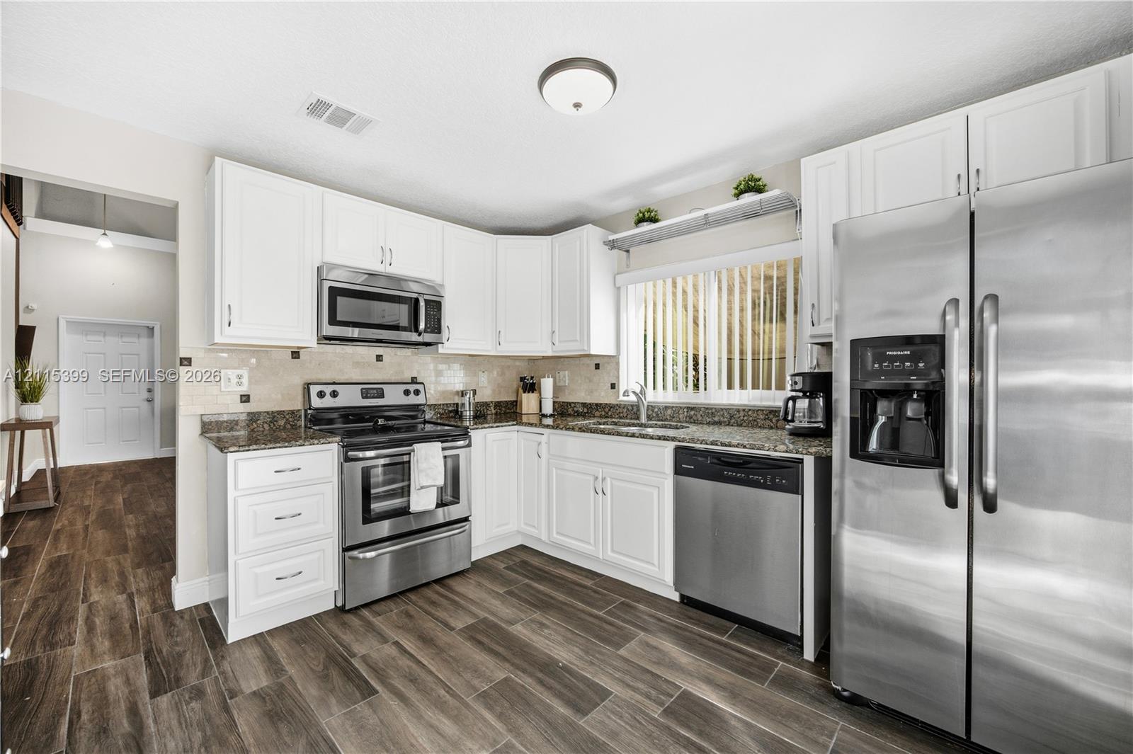 Kitchen featuring white cabinetry, stone-surface countertops, stainless steel appliances, and wood-finish flooring