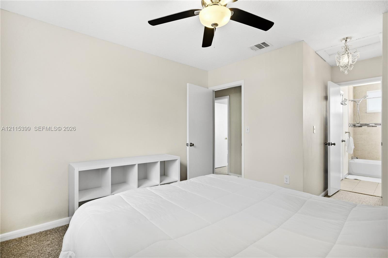 Bedroom featuring neutral wall paint, carpeting, a ceiling fan with integrated lighting, and a crystal-style flush mount light fixture
