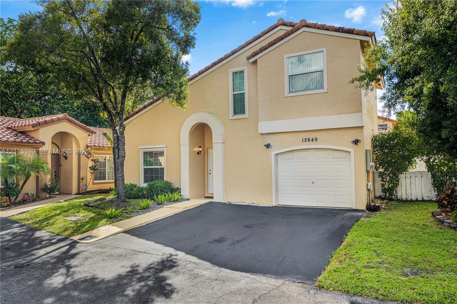 Two-story exterior featuring a tiled roof, arched entryway, and single-car garage