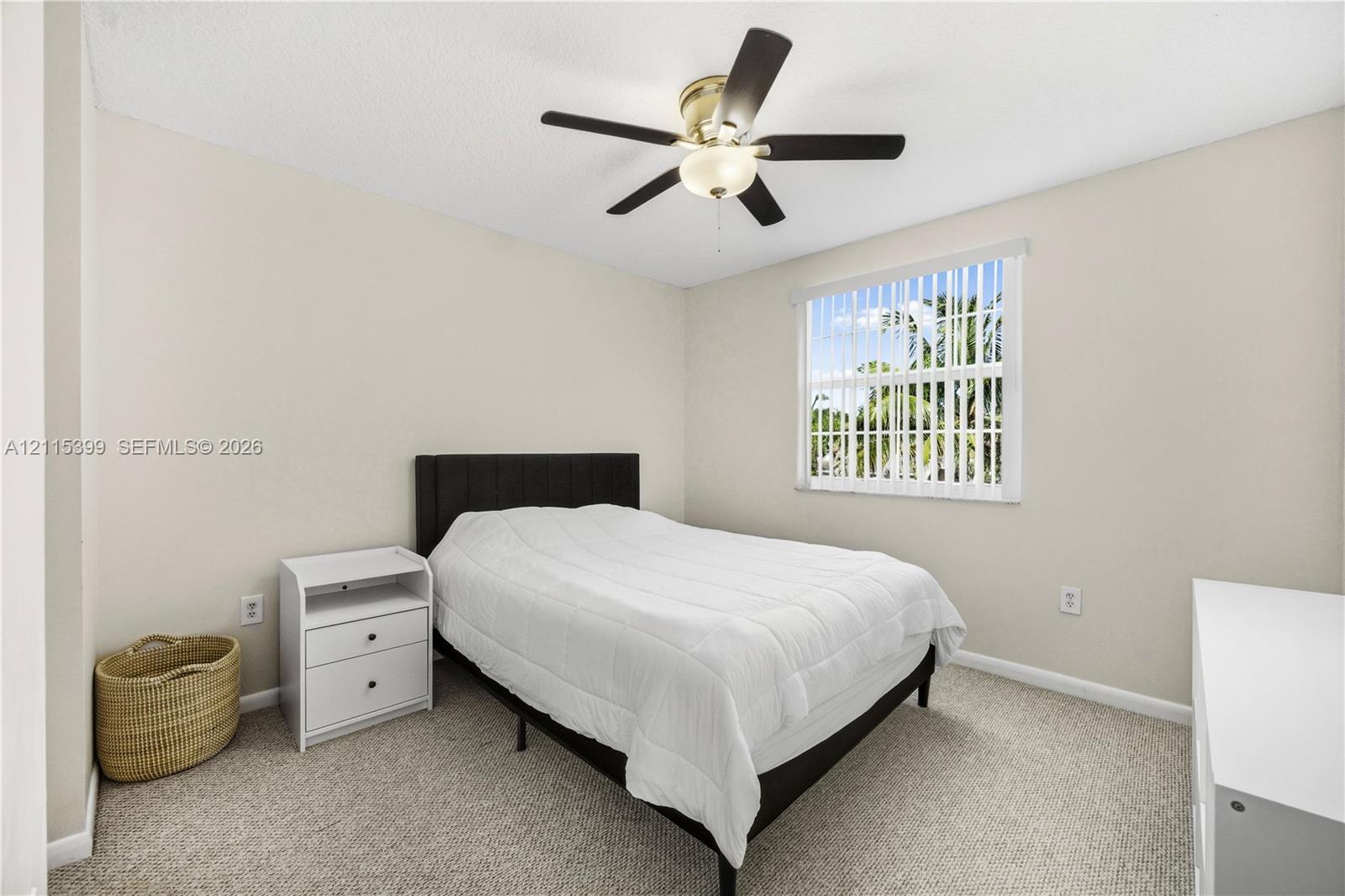 Neutral-toned walls, wall-to-wall carpeting, window with vertical blinds, and a ceiling fan with integrated lighting fixture