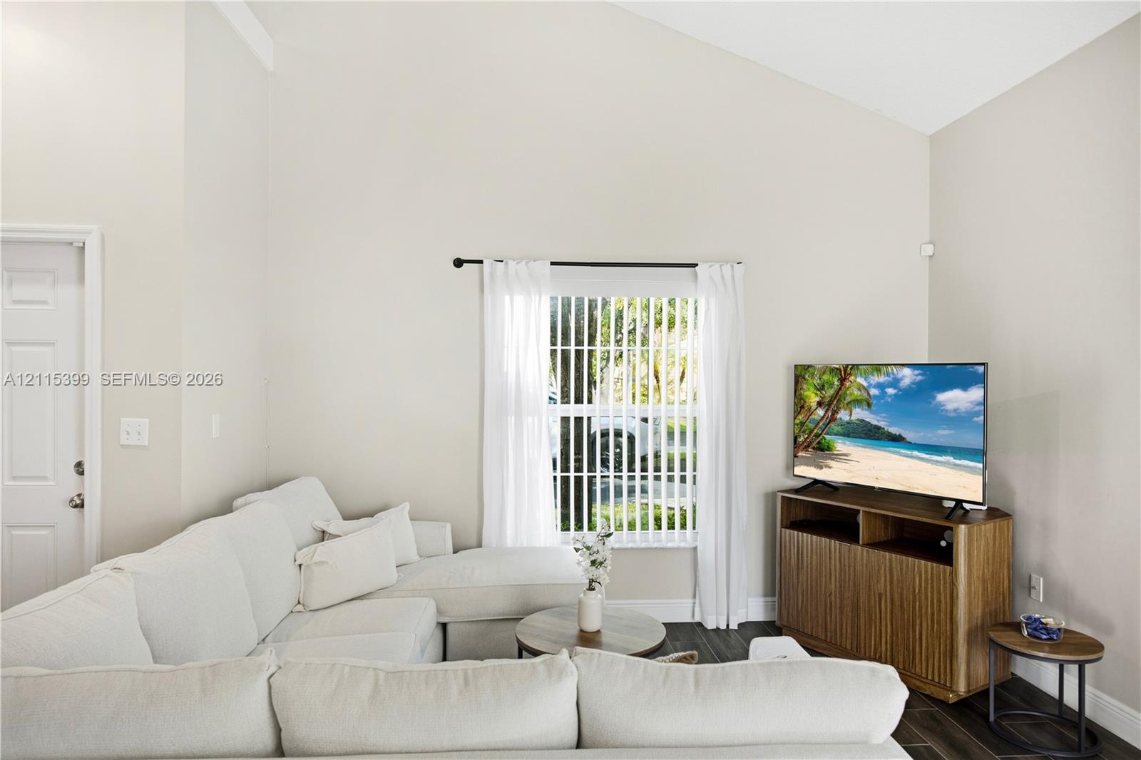 Vaulted ceiling, neutral wall color, and vertical blinds