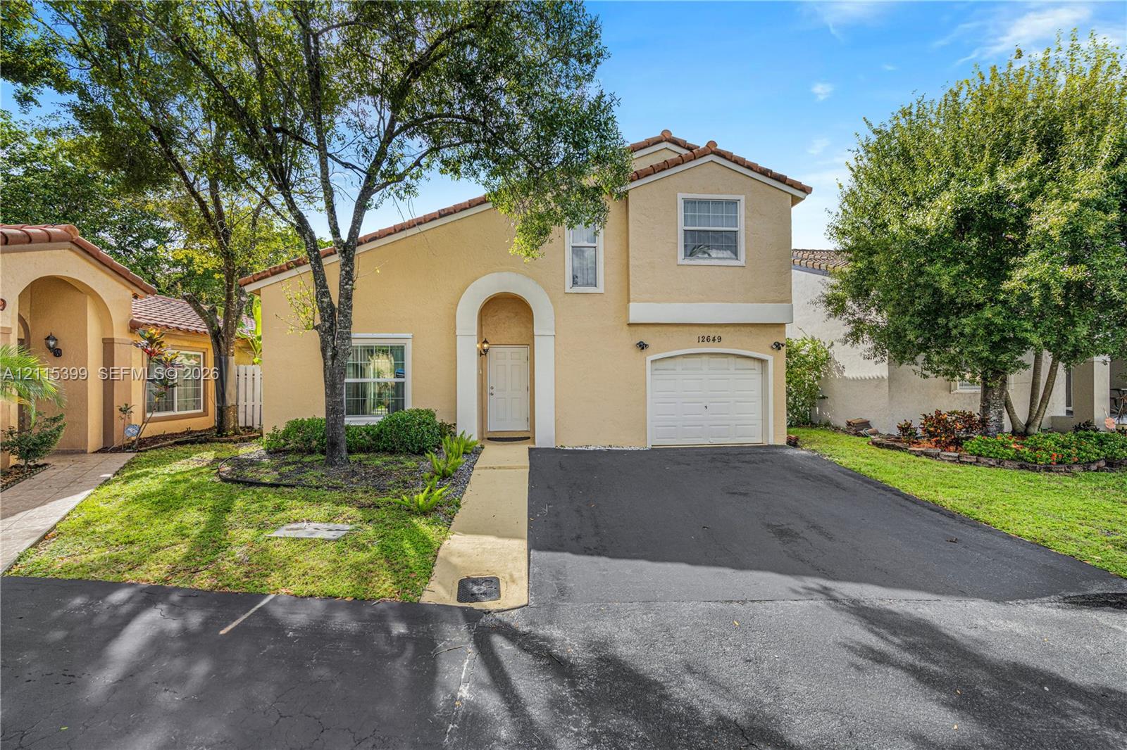Exterior residence featuring a tiled roof, arched entryway, single-car garage, and a paved driveway Exterior residence featuring a tiled roof, arched entryway, single-car garage, and a paved driveway