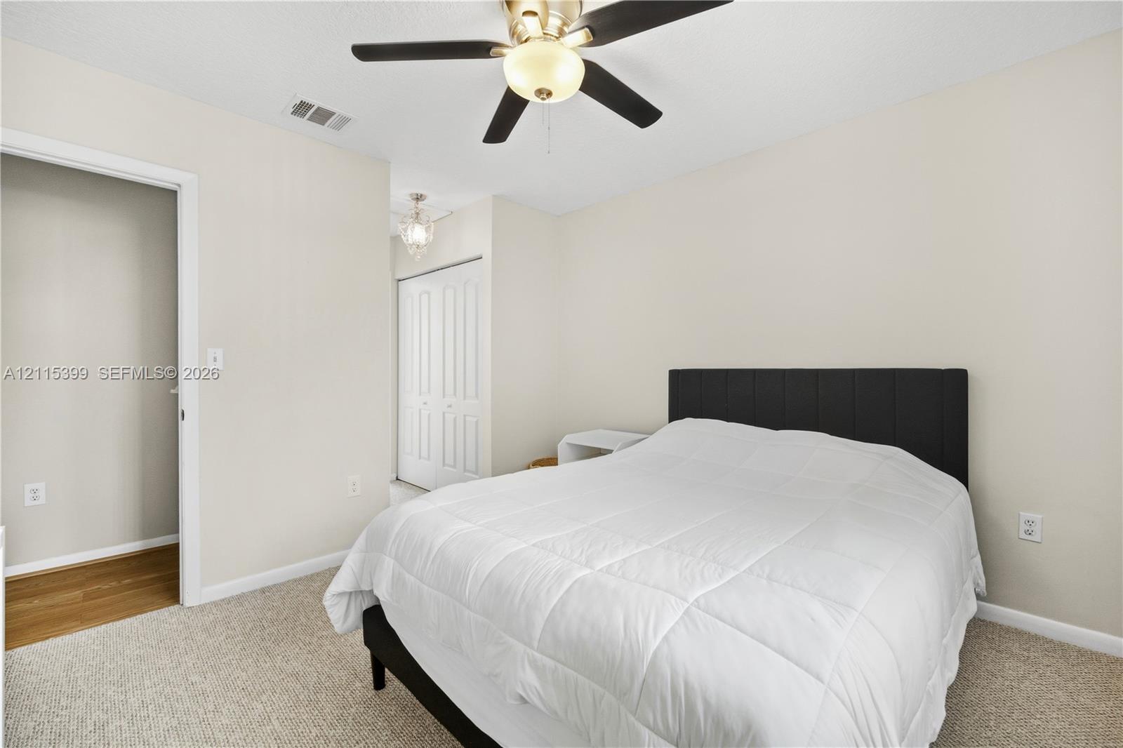 Room featuring neutral wall tones, wall-to-wall carpeting, a ceiling fan with integrated light fixture, and a reach-in closet with double doors