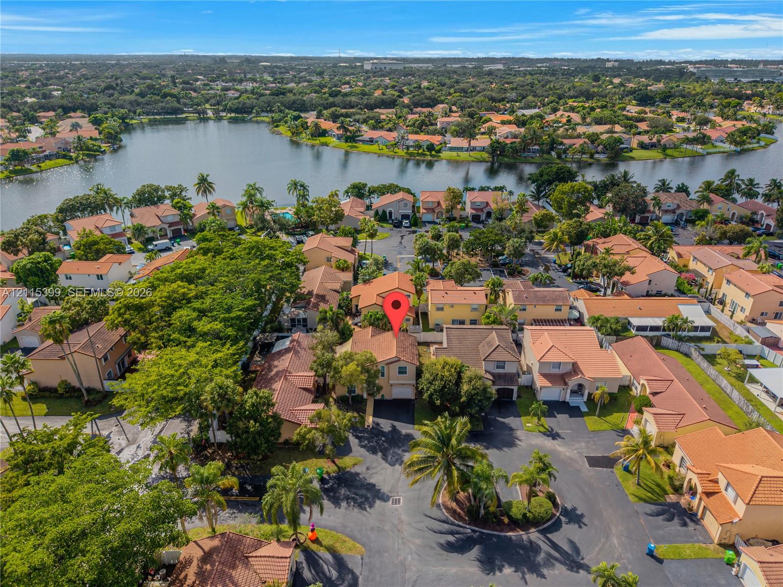 Aerial perspective featuring a multi-story residence with a pitched tile roof, attached garage, and mature landscaping within a planned community