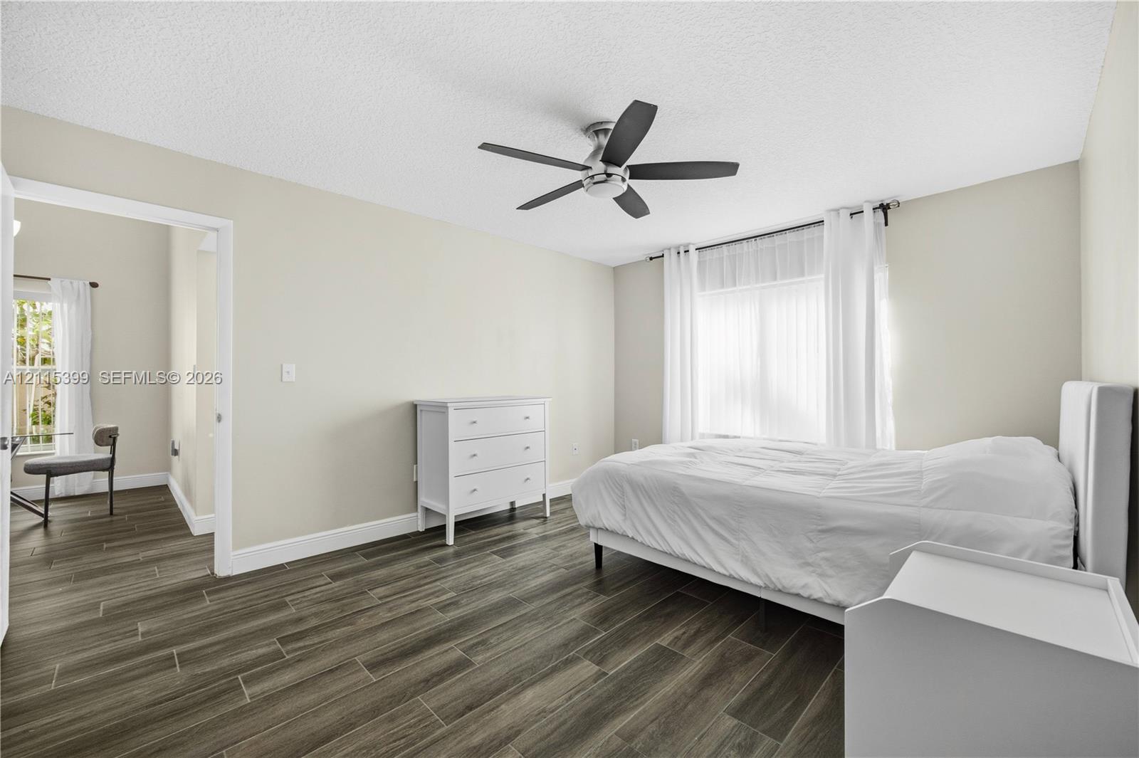 Wood-finish flooring, neutral wall color, and five-blade ceiling fan