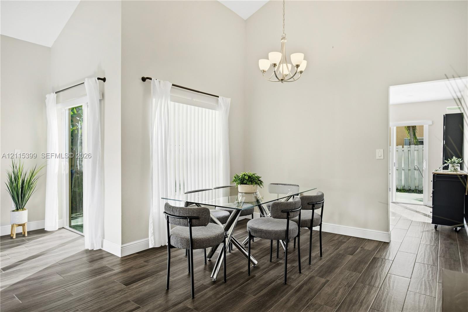 Vaulted ceilings, wood-finish tile flooring, glass sliding door, and a multi-arm chandelier