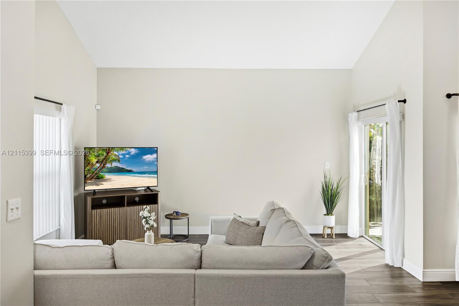 Vaulted ceiling, sliding glass doors, and wood-finish flooring