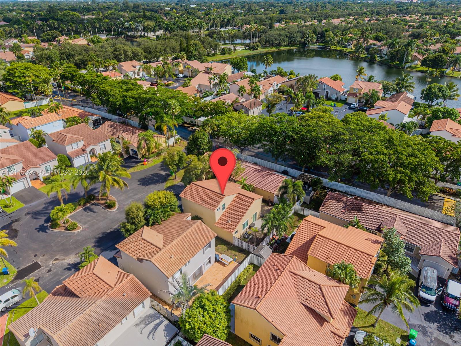 Aerial perspective of a multi-level residence featuring a clay tile roof, stucco exterior, and a fenced rear outdoor area