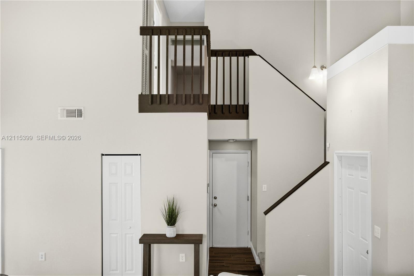 High-ceiling foyer featuring a staircase with wood-finish balusters, a hanging pendant light fixture, and paneled interior doors