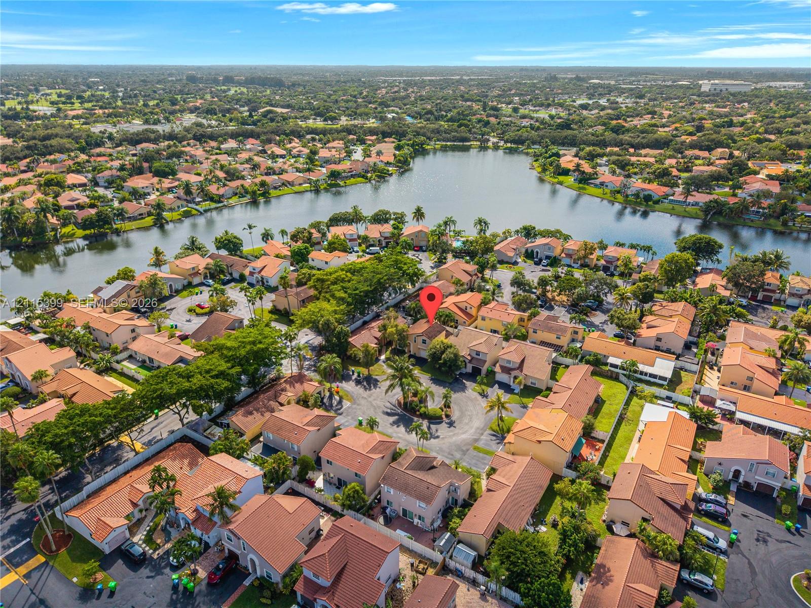 Aerial perspective featuring a multi-story residence with a concrete tile roof, situated within a cul-de-sac setting surrounded by a landscaped residential neighborhood