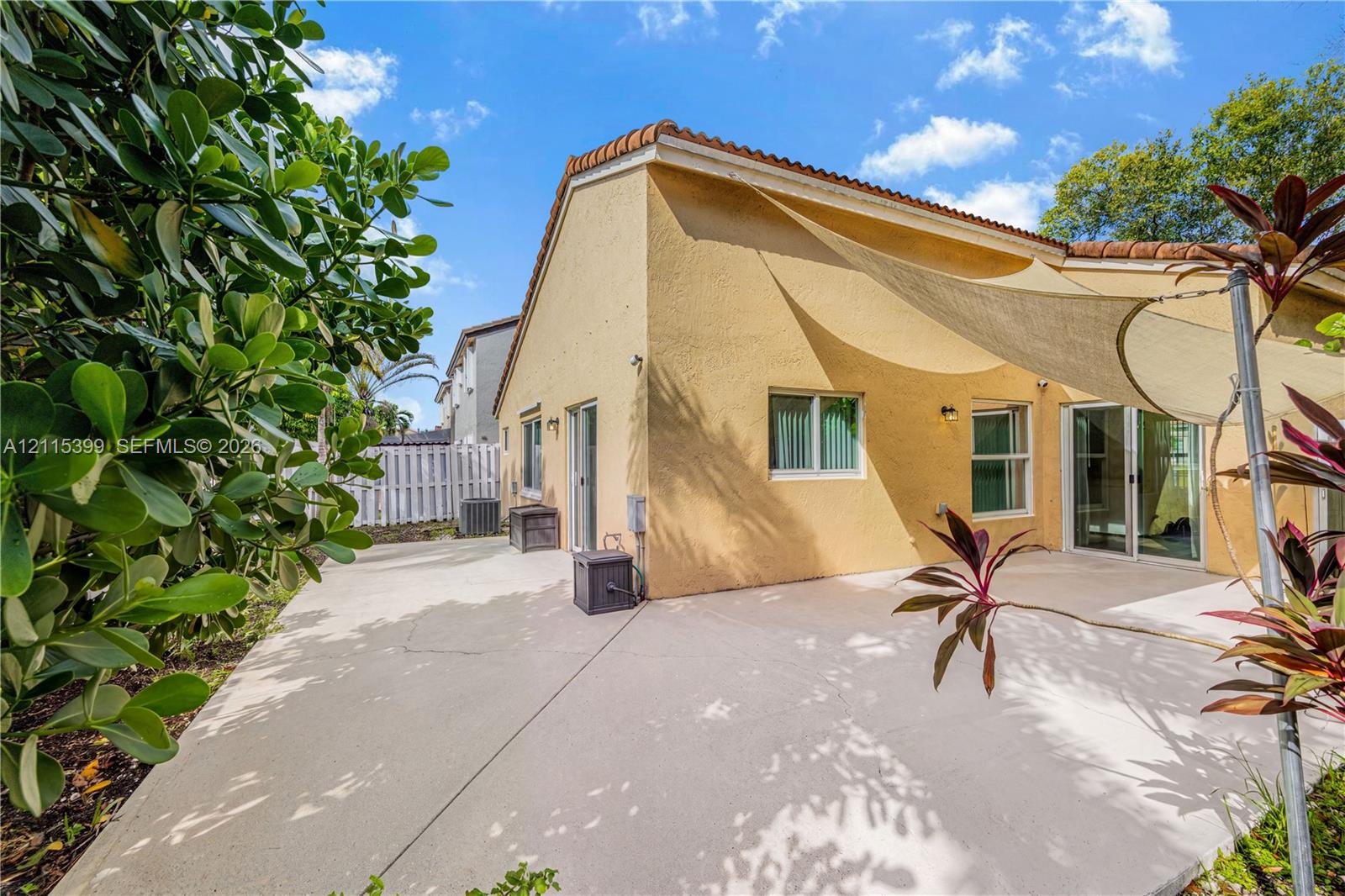 Stucco exterior featuring a concrete patio, sliding glass doors, and a tile roof