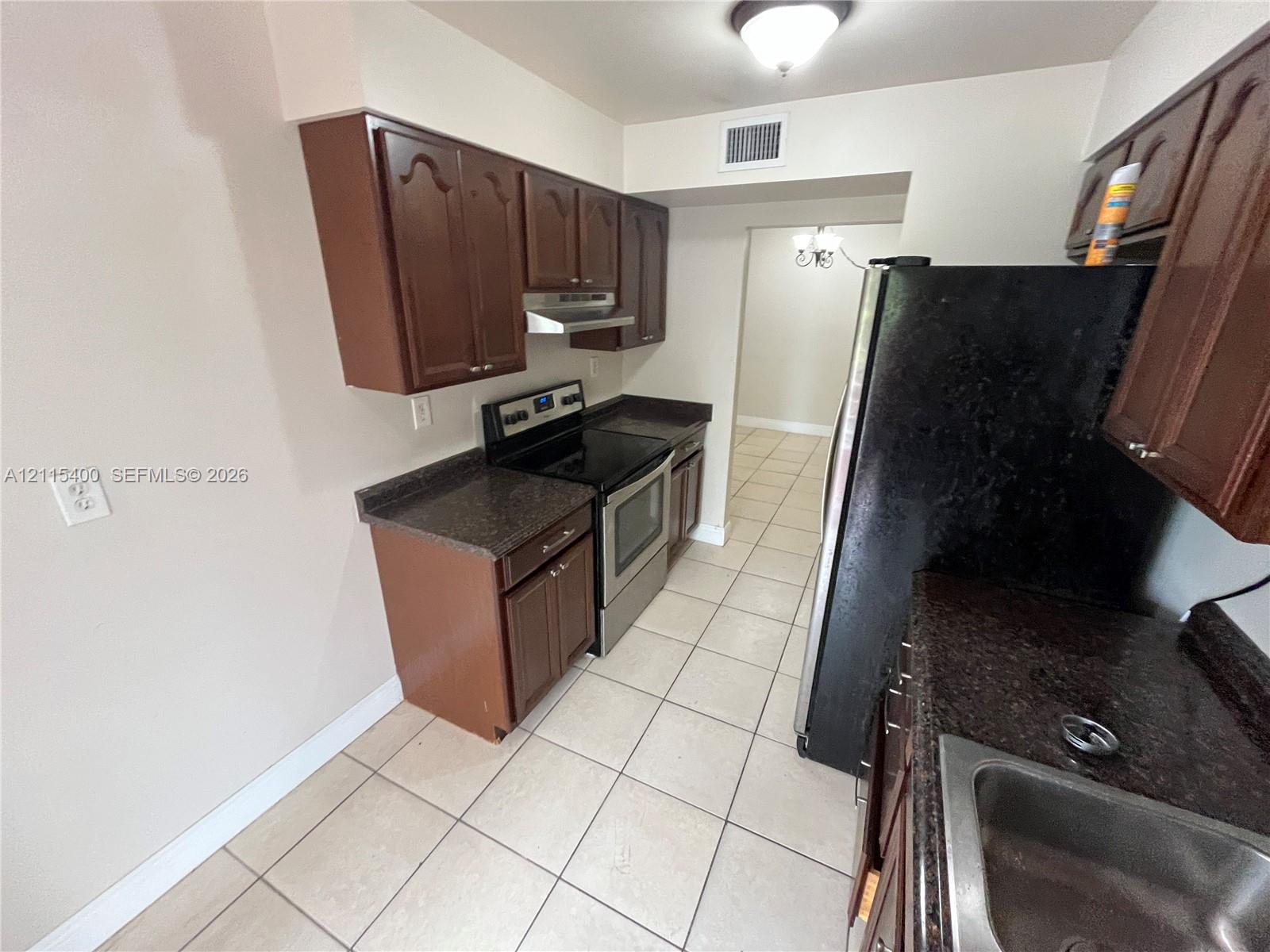 Kitchen featuring dark-toned cabinetry, stone-finish countertops, tile flooring, and stainless steel range