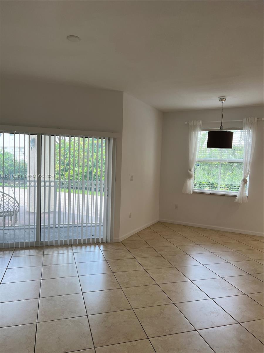 Neutral ceramic tile flooring, large sliding glass door, and overhead pendant lighting fixture