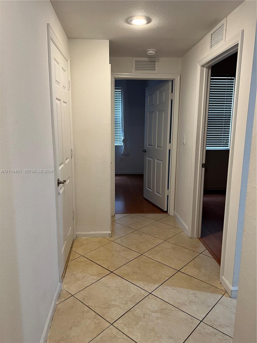 Neutral-toned tile flooring set in a diagonal pattern, complemented by six-panel interior doors and recessed lighting