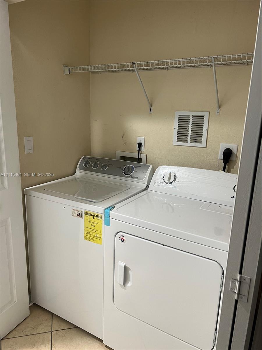 Dedicated laundry area featuring tile flooring and an integrated wire shelving unit