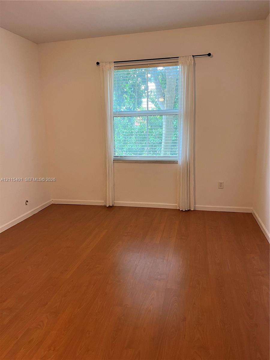 Interior room featuring wood-finish flooring, neutral wall tones, and a single window with integrated blinds