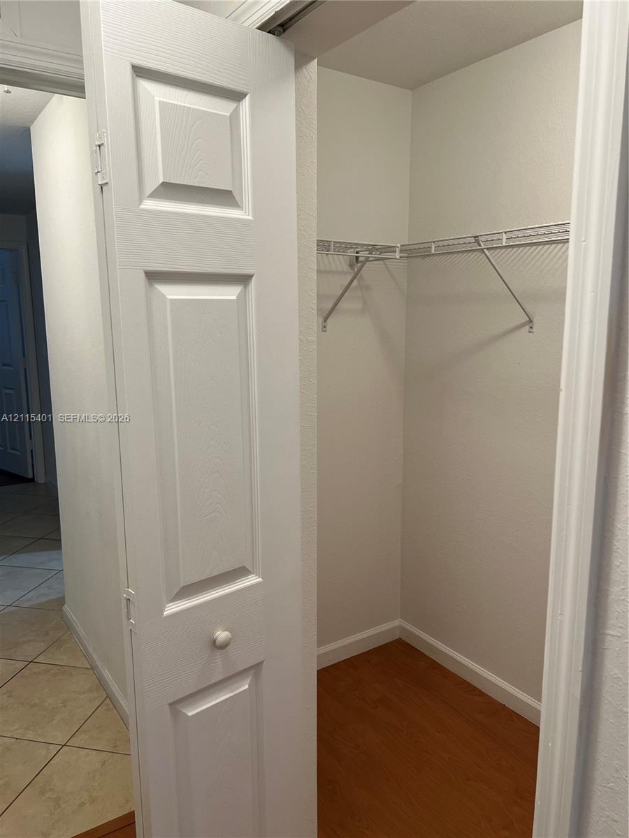 Storage closet featuring a white four-panel bi-fold door, wood-finish flooring, and white wire shelving