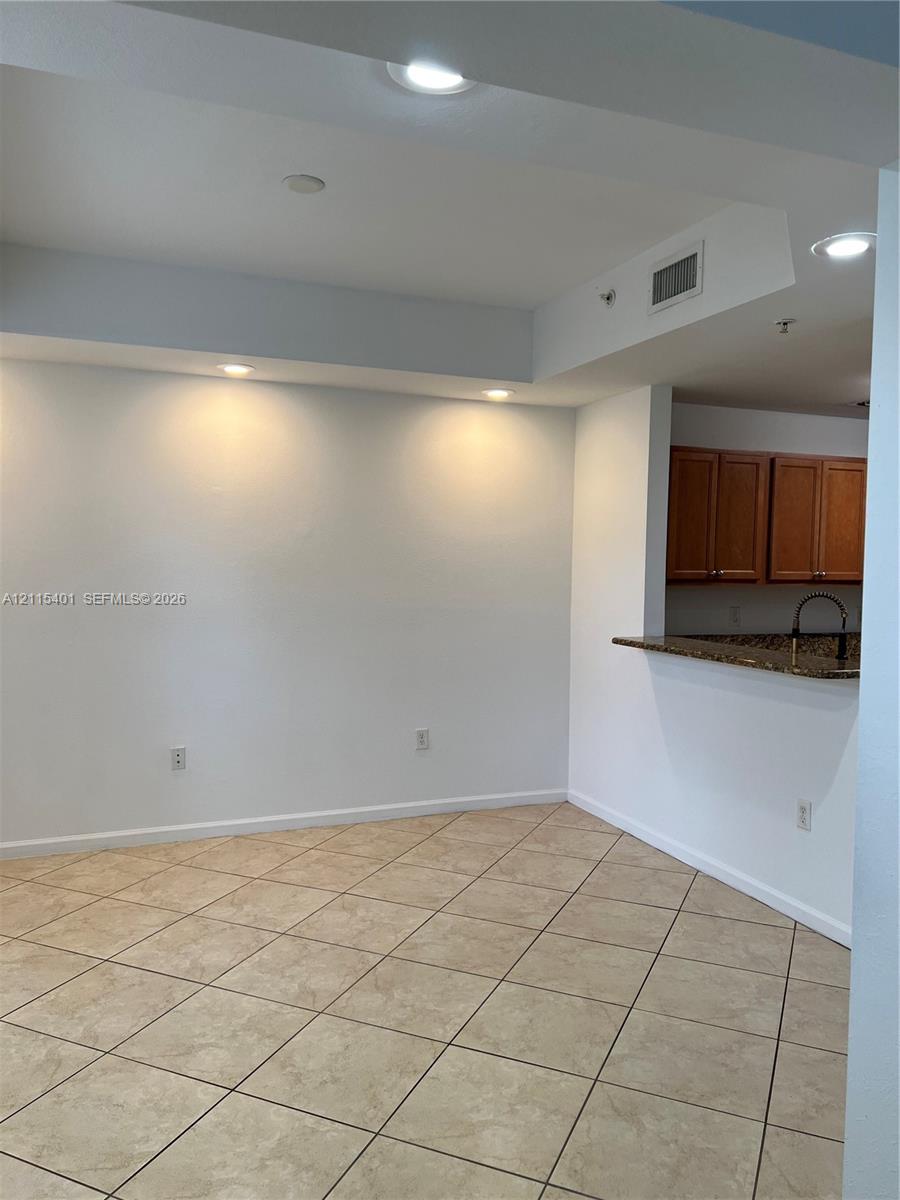 Tile flooring, recessed lighting, and a kitchen pass-through counter featuring stone-surface countertops and wood-finish cabinetry