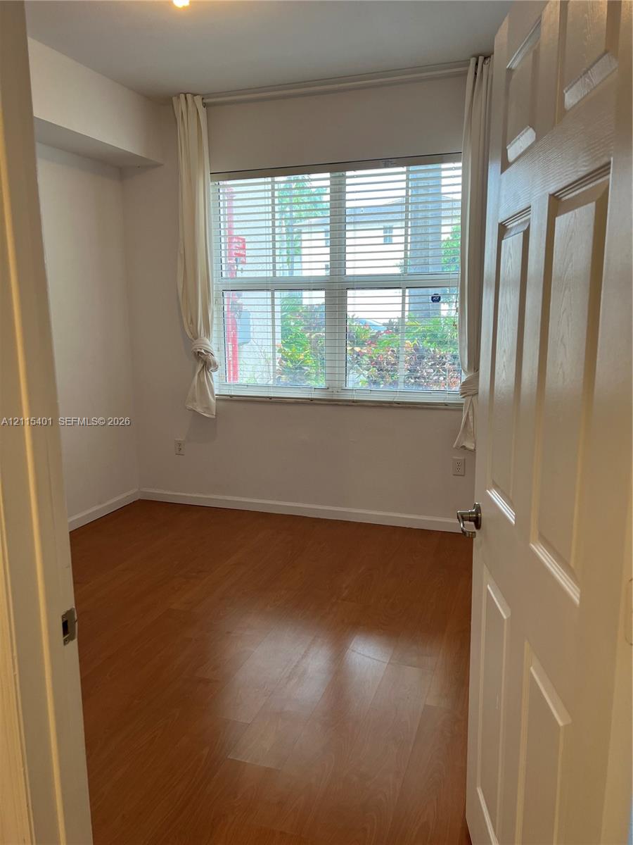 Room featuring wood-finish flooring, a large multi-pane window, and white interior walls