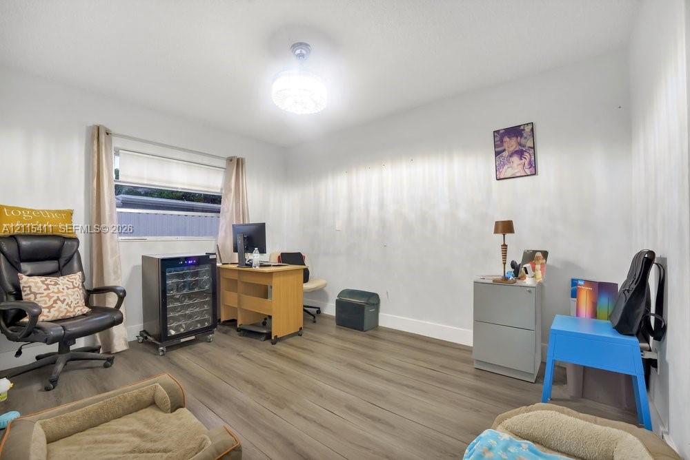 Wood-finish flooring, horizontal window with roller shade, and ceiling-mounted light fixture