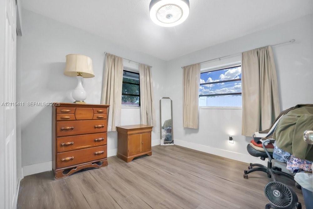 Neutral interior featuring wood-finish flooring, two horizontal-slider windows, and a flush-mount ceiling light fixture