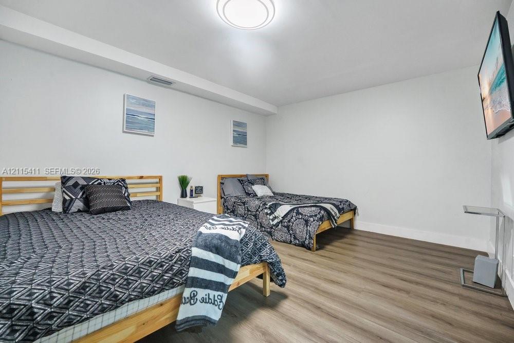 Spacious room featuring wood-finish flooring and a flush-mount ceiling light fixture