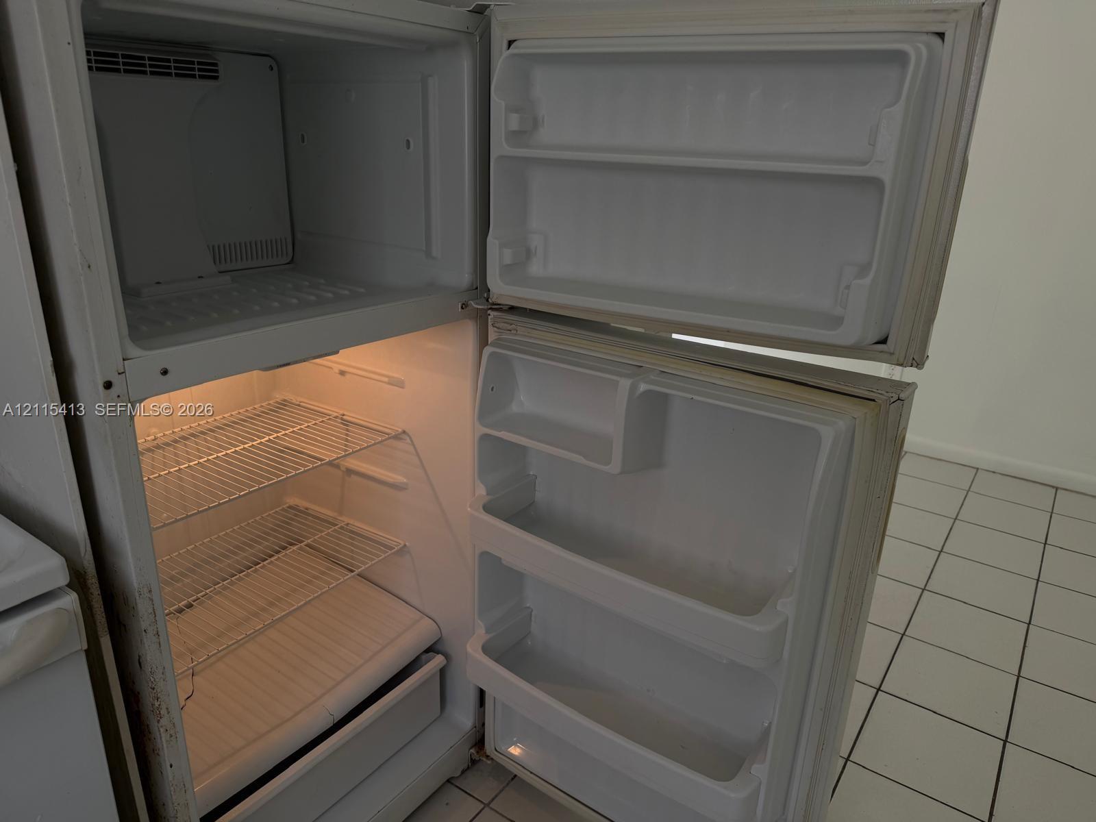 Top-mount refrigerator featuring wire shelving, door storage bins, and interior lighting