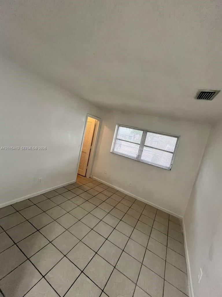 Neutral wall finish, ceramic tile flooring, and horizontal sliding window with metal frame