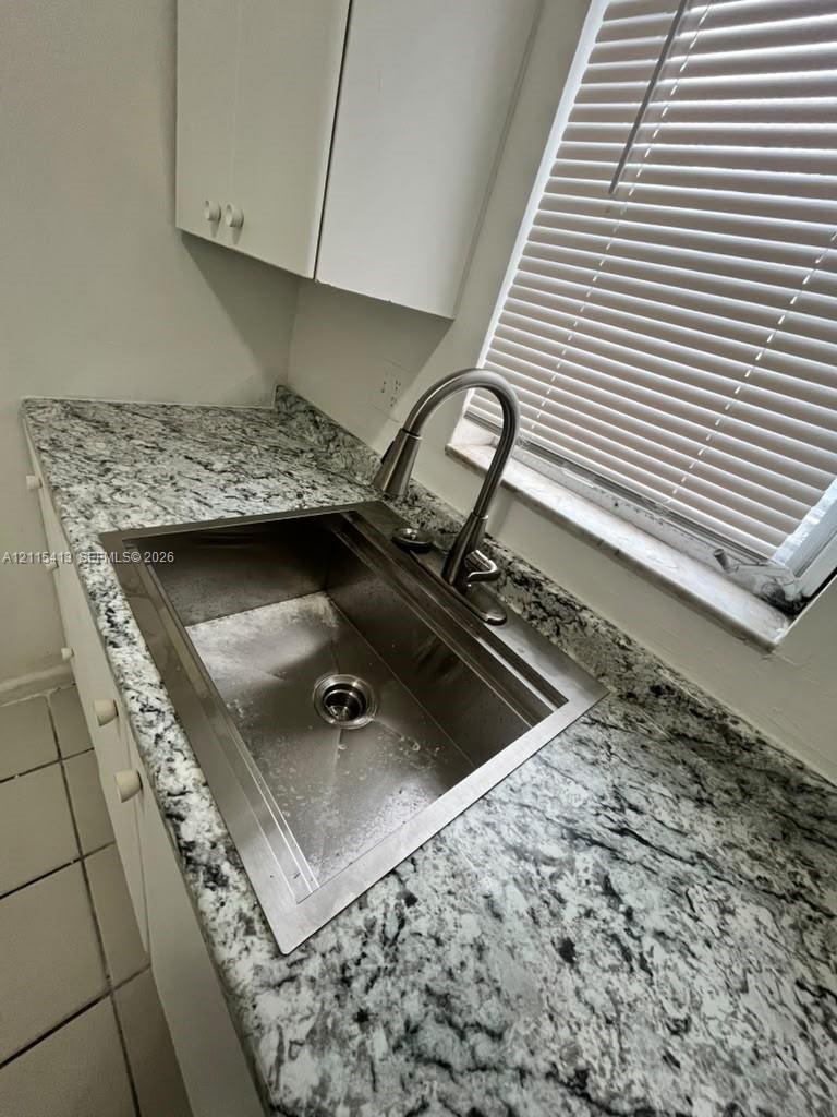 Stone-surface countertops paired with a deep stainless steel basin, high-arch pull-down faucet, and white cabinetry