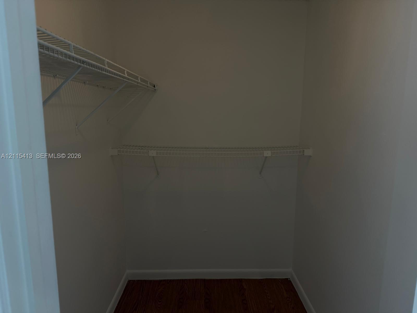 Reach-in closet featuring tiered wire shelving and wood-finish flooring