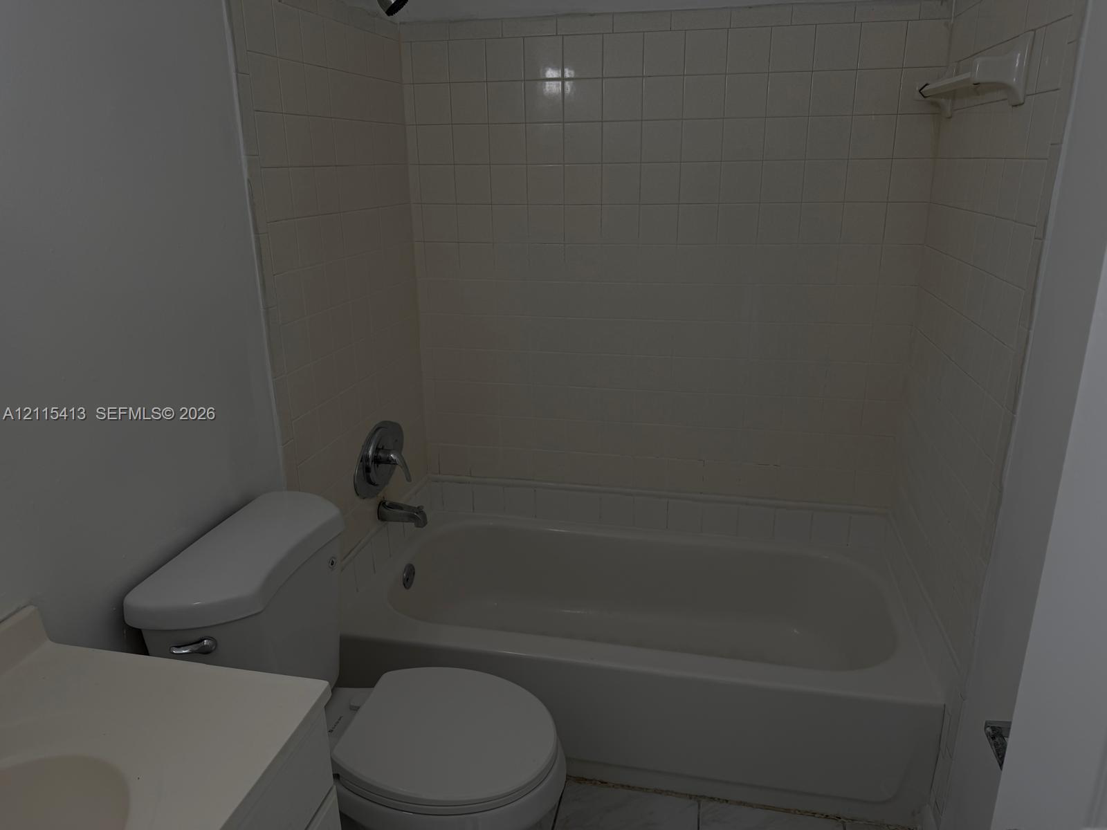 Bathroom featuring a tub and shower combination with tile surround, porcelain toilet, and vanity with an integrated basin