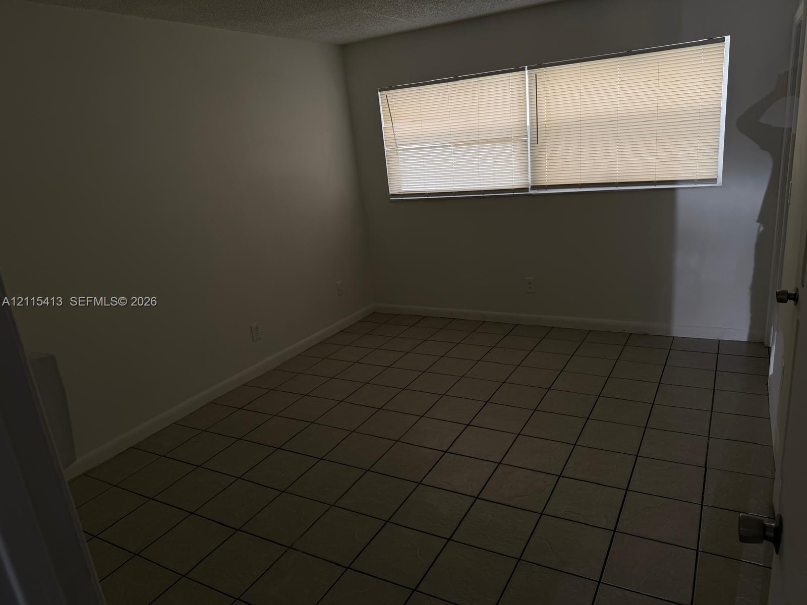 Interior space featuring neutral-toned tile flooring, light-colored walls, and large horizontal windows equipped with integrated blinds