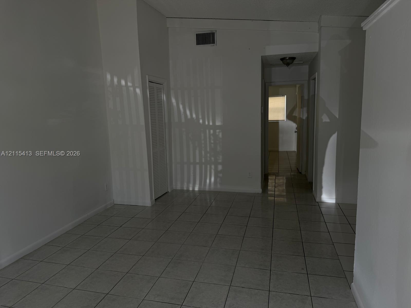 Interior space featuring white walls, ceramic tile flooring, a louvered closet door, and a flush-mount ceiling light fixture